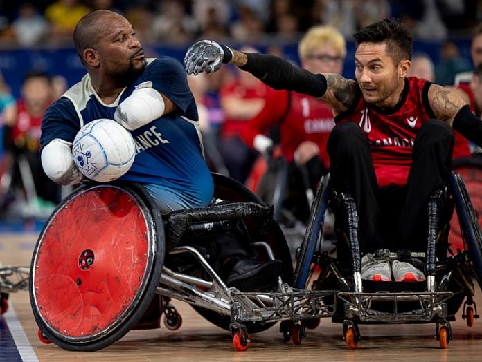 Two male wheelchair rugby athletes in competition. 